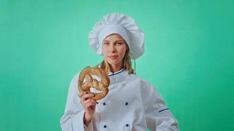 Excited baker with a pretty face in a green studio eating with lust a fresh Video stock 125487652
