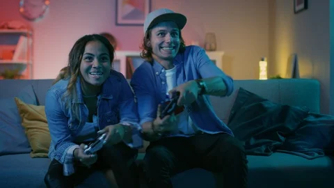 Excited Black Gamer Girl and Young Man Sitting on a Couch and Playing Video Game Stock Footage