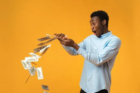 Excited black guy holding stack of Dollars in yellow studio 스톡 사진