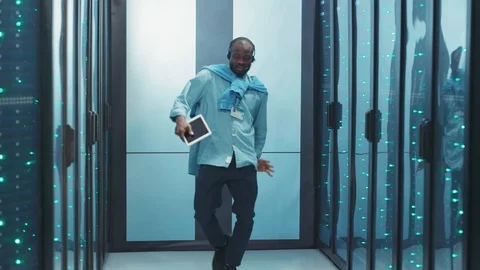 Excited black IT administrator dancing in server rack corridor happy with Stock Footage 119783619