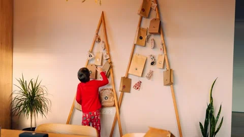 Excited boy joyfully opening a gift bag from a wooden advent calendar Stock Footage 289198059