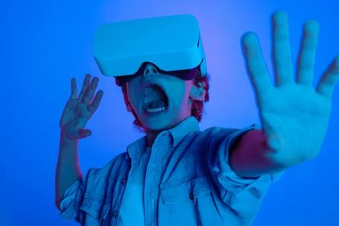 Excited Boy Using Virtual Reality Headset in Vibrant Lighting Stock Photos