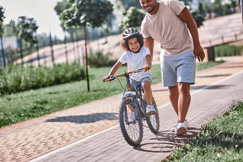 Excited child learning cycle with a help of his dad Stock Photos