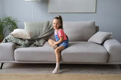 Excited child looking at camera while sitting in living room at home. Foto stock