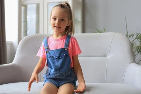Excited child looking at camera while sitting in living room at home. Foto stock
