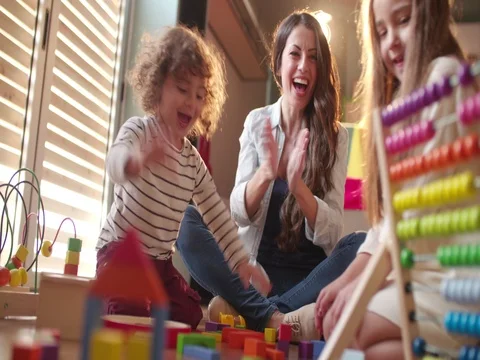 Excited children and babysitter playing with toys on the floor Stock Footage