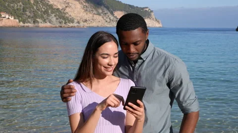 Excited couple checking phone celebrating on the beach Stock Footage 171229088