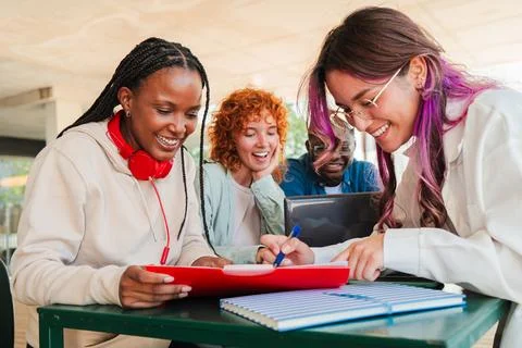 Excited diverse students engaged in collaborative learning while studying Stock Photos