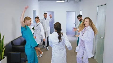 Excited doctors and nurses with a large smile dancing in front of the camera in Stock Footage 139869211