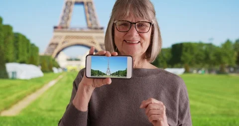 Excited elderly white lady showing off photo she took of Eiffel Tower on phone Stock Footage 88561188