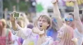 Excited friends covered in colorful powder at paint festival, posing for selfie 4k or 4k+ Resolution