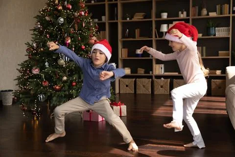 Excited funny kids dancing to music at Xmas tree Stock Photos