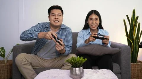 Excited funny young couple playing video games holding game controller sittin Foto stock