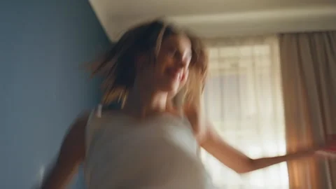 Excited girl jumping bed at home closeup. Happy brunette in pajamas having fun Vidéo 281184341