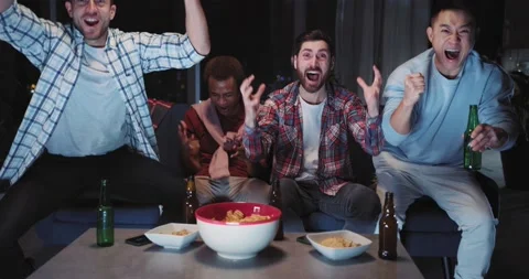 Excited group of multi-ethnic guys watching football match on TV cheering for Stock Footage 148111118