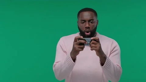 Excited guy playing games on mobile phone on Green Screen, Chroma Key Stock Footage 142157444