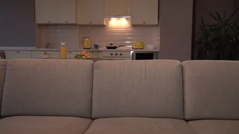 Excited guy is sitting on sofa and turning on tv using remote control. He put Stock Footage 99739250