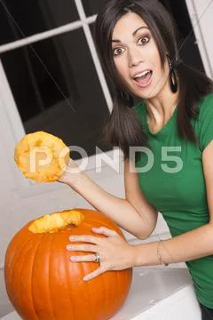 Excited happy woman cutting carving halloween pumpkin jack-o-lantern Stock Photos