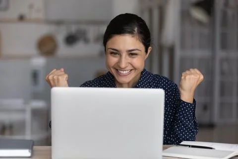 Excited Indian woman triumph with good news on laptop Stock Photos