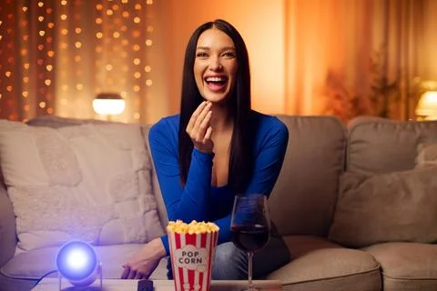 Excited lady laughing while watching comedy movie at home, eating popcorn and Stock Photos