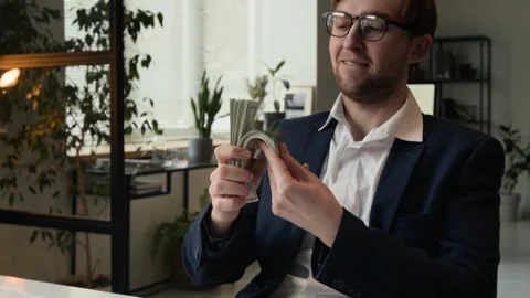 Excited Man Bringing Stack of Money Close to Face and Kissing in Office Setting Stock Footage 331534278