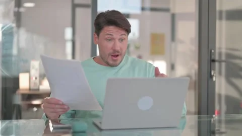 Excited Man Celebrating Success while Multi Tasking at Work Stock Footage 261961035