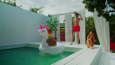 Excited man in inflatable ring jumping into pool Stock Footage 139145186