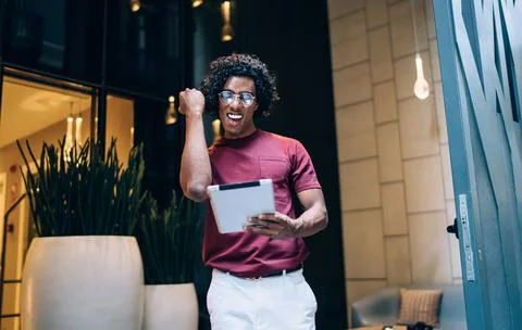 Excited man in spectacles using digital tablet for reading great web news in Stock Photos