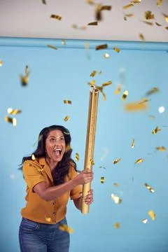 Excited Mature Woman Celebrates Winning Firing Gold Confetti Canon In Studio Stock Photos