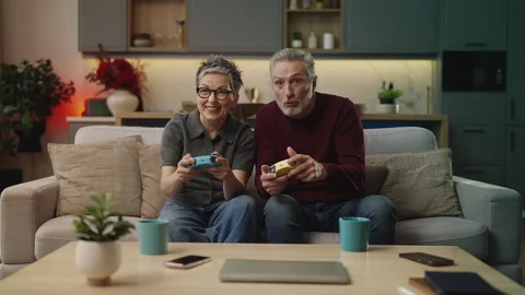 Excited middle-aged couple playing video game with gamepads, having fun at home Stock Footage 340919580