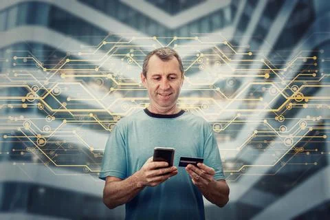 Excited middle aged man using a smartphone while holds his credit card, brows Stock Photos