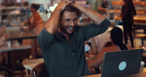 Excited multi-ethnic attractive bearded guy, sitting at a table in a cafe and Stock-Footage 218566231