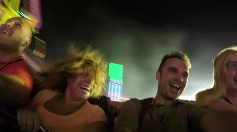 Excited people having fun on rollercoaster ride in amusement park at night Stock Footage 64514666