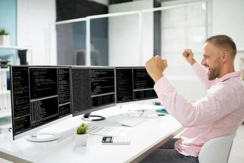Excited Programmer Using Multiple Computer Screens 写真素材