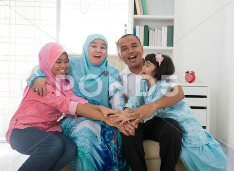 Excited southeast asian family at home. muslim family living lifestyle. Stock Photos