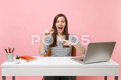 Excited woman pointing index finger on bitcoin, metal coin of golden color Stock Photos