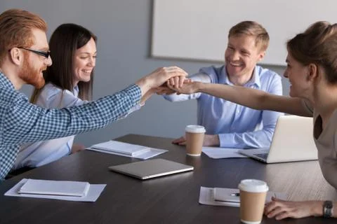 Excited workers join hands engaged in teambuilding activity Foto stock