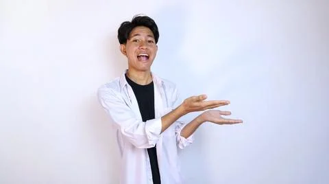 Excited young Asian man gesturing to the side using the palm of his hand 写真素材