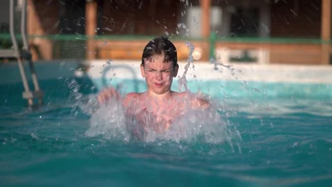 Excited young boy hits pool water with both hands 動画素材 342193538