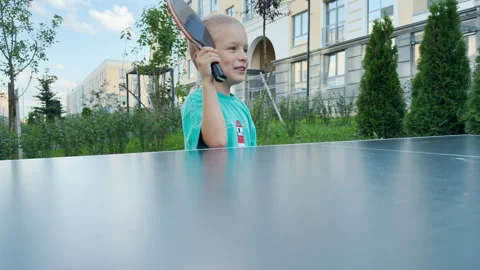An excited young boy raises his ping pong paddle high with joy. Stock Footage 344968498