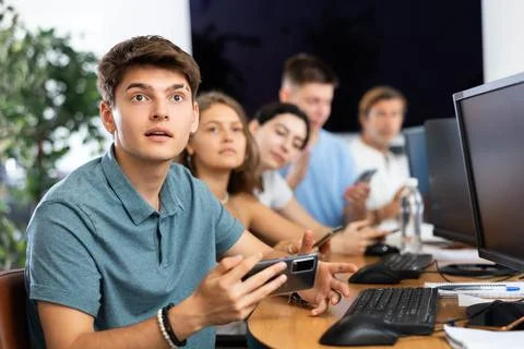 Excited young developer using mobile phone at IT startup presentation Stock Photos