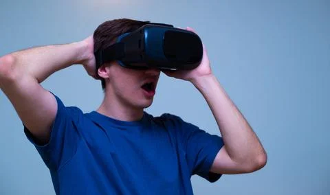An excited young guy in virtual reality glasses is immersed in the metaverse Stock Photos