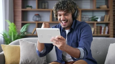 Excited young handsome man in wireless headphones watching sports match  Stock Footage 296762671