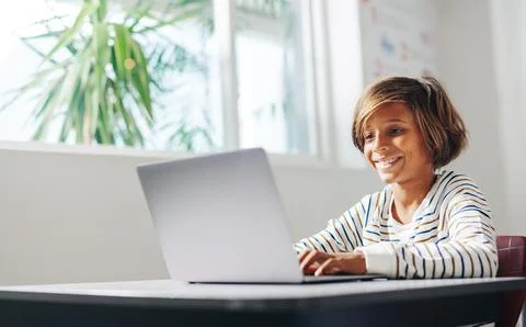 Excited young kid learning to code with a laptop in a classroom Foto stock