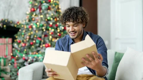 An excited young man customer opens a package at home during winter New Year  Stock Footage 253265304