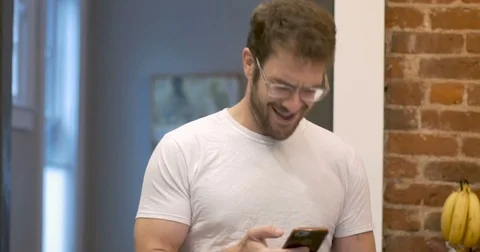 Excited young man getting good news on his smart watch and mobile phone Stock Footage 82270833