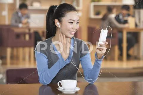 Excited young woman listening to music at a coffee shop Stock Photos