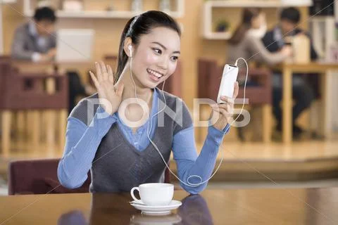 Excited young woman listening to music at a coffee shop Stock Photos