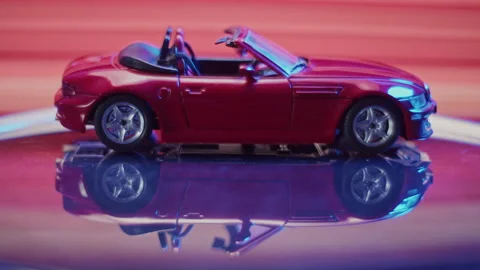 Exciting display of a shiny red toy model car in dynamic lighting Stock Footage 319902805