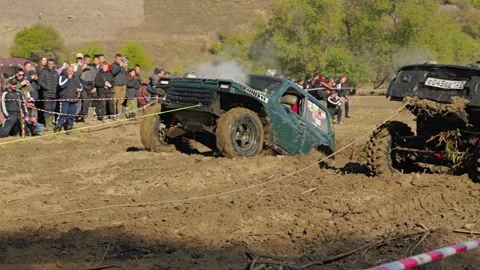Exciting off-road racing scene with two modified 4x4 trucks stuck in a muddy Stock Footage 345494515